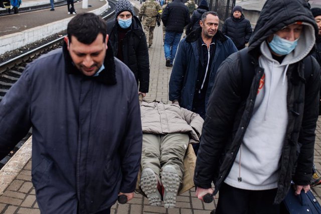 Quatre hommes portent sur une civière une femme venue de la ville de Kharkov, le 4 mars 2022, à la gare de Lviv, en Ukraine. L'Ukraine est plongée dans un conflit qui dure depuis neuf jours, après que la Russie a commencé à attaquer la ville de Kharkov le 4 mars 2022.