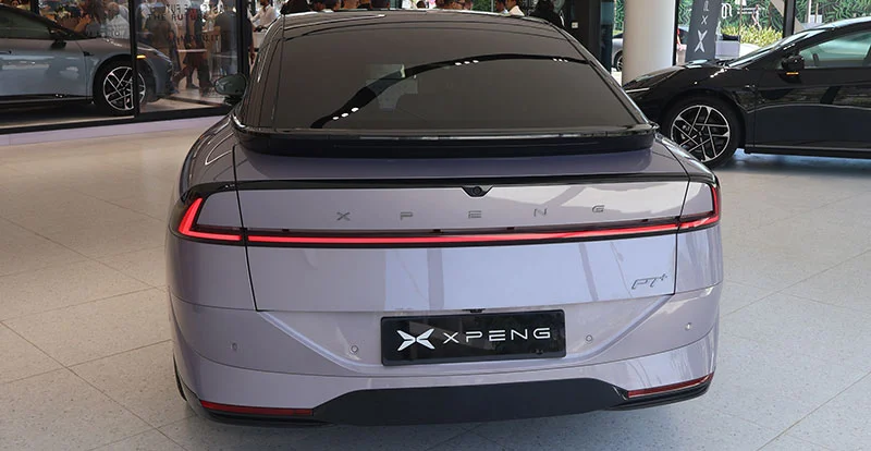L'arrière de la XPENG P7+ 2026 s'illumine d'un bandeau LED continu, surmonté d'un becquet intégré au hayon et d'une lunette fortement inclinée.